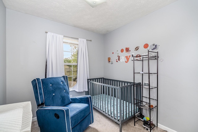 carpeted bedroom with a textured ceiling, a crib, and baseboards