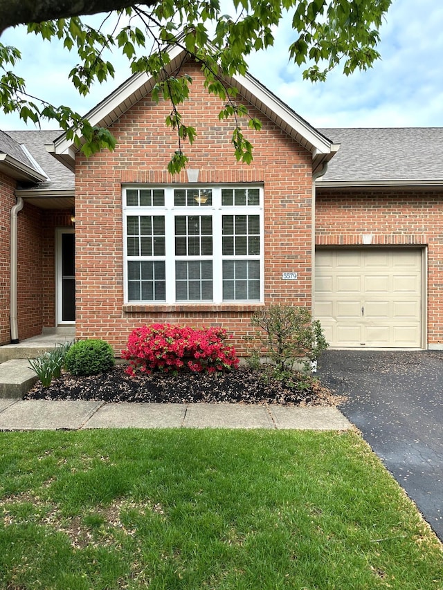 view of front of home with aphalt driveway, an attached garage, a shingled roof, and brick siding