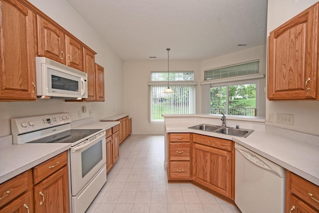 kitchen featuring a sink, brown cabinets, white appliances, and light countertops