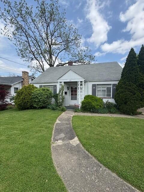 view of front of property with a chimney and a front lawn