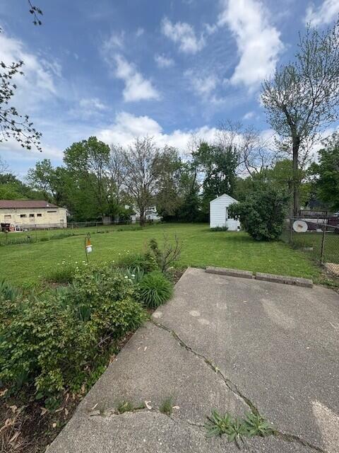 view of yard with a storage shed, fence, and an outbuilding
