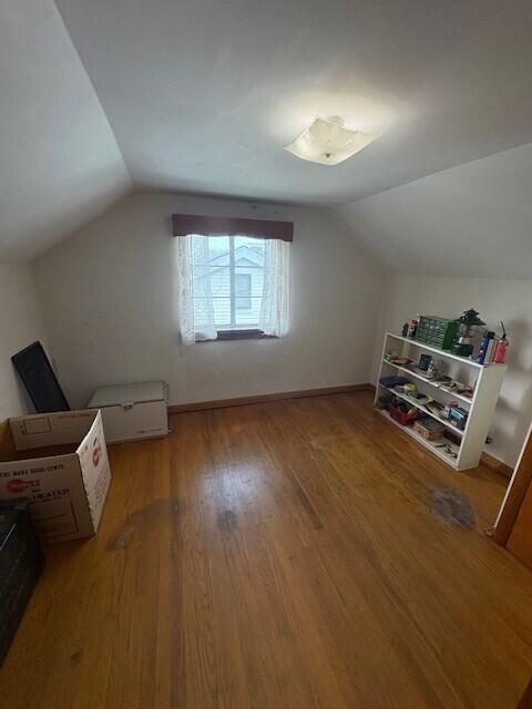 additional living space featuring wood finished floors and lofted ceiling