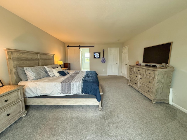 bedroom featuring light colored carpet, baseboards, and a barn door