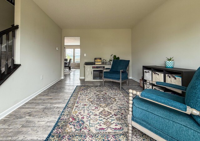 living area featuring stairway, wood finished floors, and baseboards