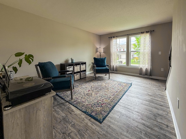 sitting room featuring wood finished floors, a textured ceiling, and baseboards