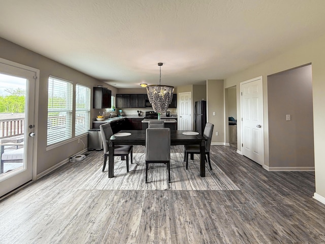 dining space with a chandelier, baseboards, and wood finished floors
