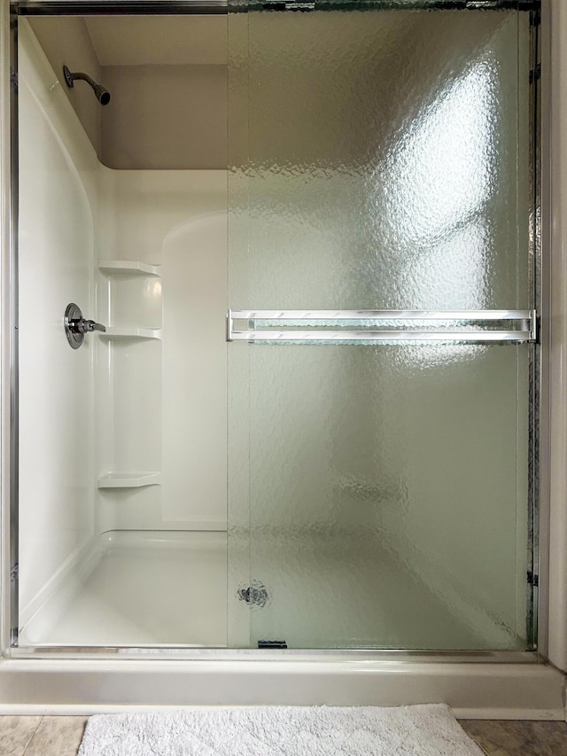 bathroom with a shower stall and tile patterned flooring