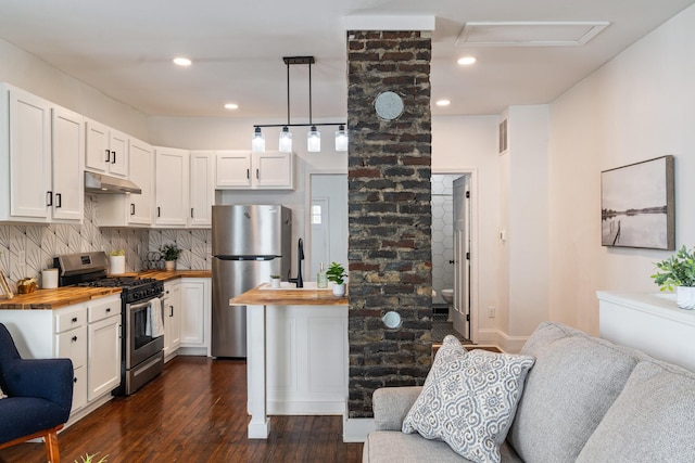 kitchen featuring wooden counters, under cabinet range hood, white cabinets, tasteful backsplash, and appliances with stainless steel finishes