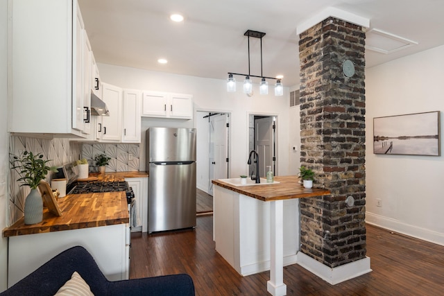 kitchen with stainless steel appliances, a sink, extractor fan, and butcher block counters