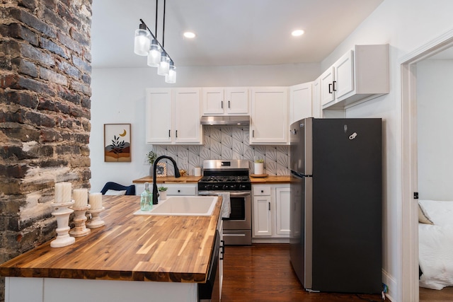 kitchen with white cabinets, a sink, stainless steel appliances, under cabinet range hood, and butcher block counters