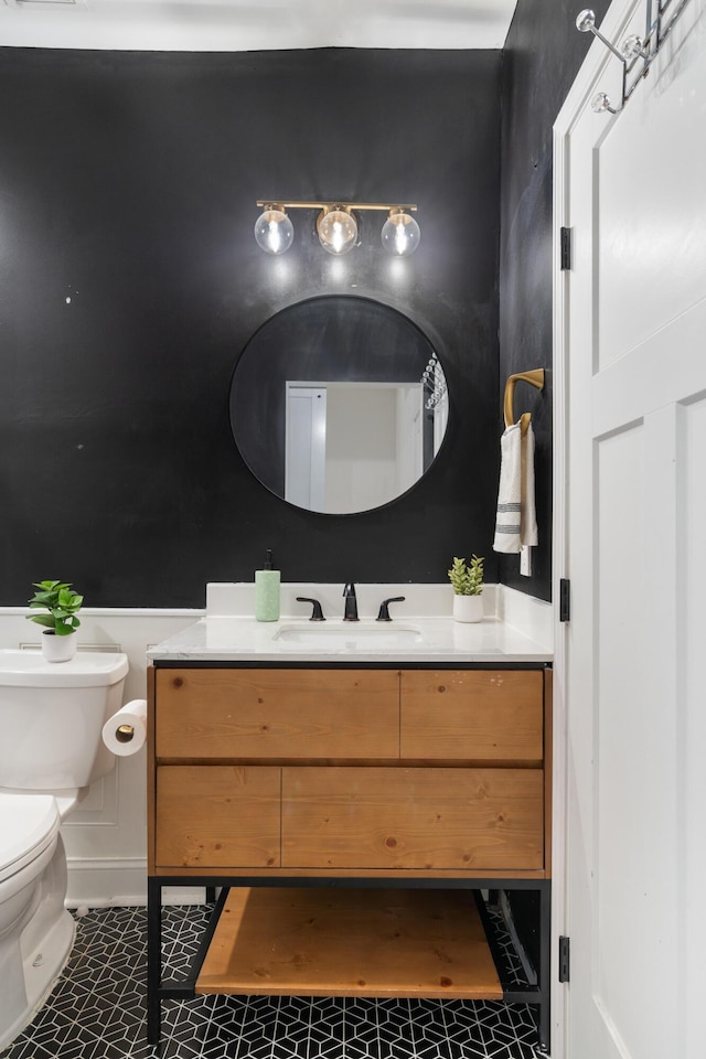 half bath with toilet, tile patterned floors, and vanity
