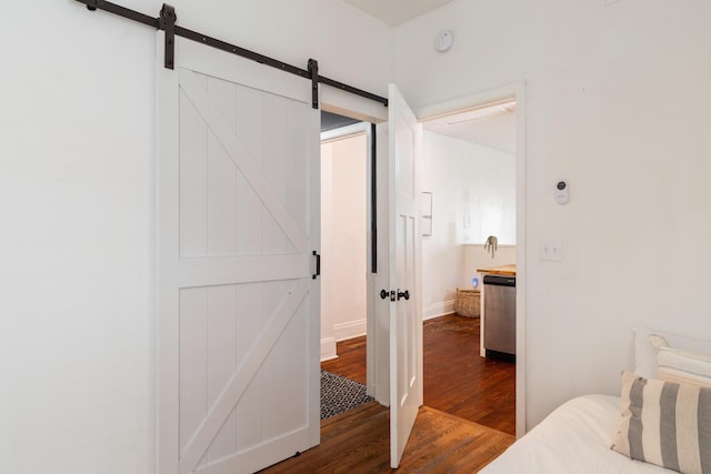 bedroom featuring dark wood-type flooring, a barn door, and baseboards
