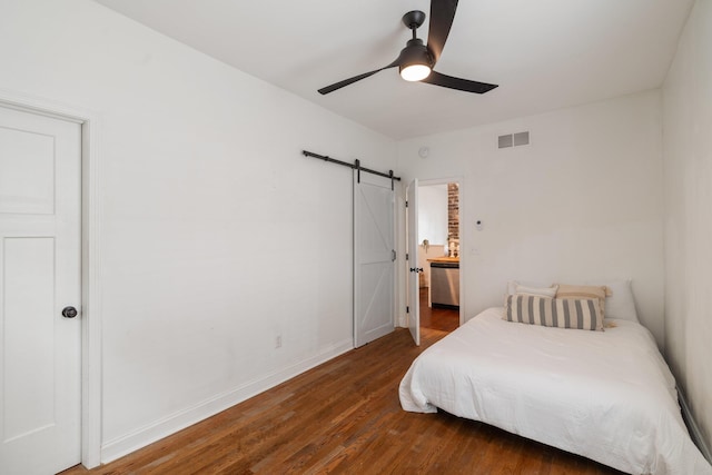 bedroom featuring a barn door, a ceiling fan, baseboards, wood finished floors, and visible vents
