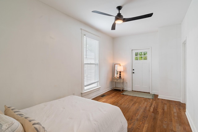 bedroom with baseboards, a ceiling fan, wood finished floors, and visible vents