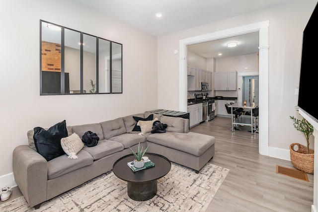 living area with recessed lighting, baseboards, and light wood finished floors