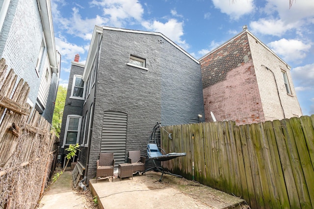 back of house featuring brick siding, a fenced backyard, and a patio area
