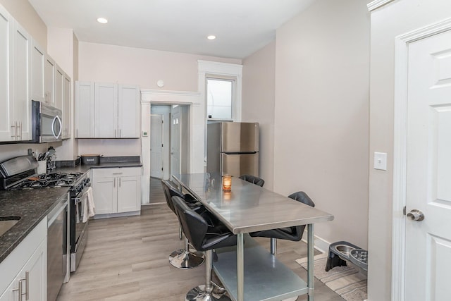 kitchen with light wood-style floors, recessed lighting, dark stone counters, and stainless steel appliances