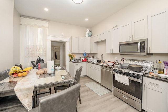 kitchen featuring recessed lighting, white cabinetry, a sink, light wood-style flooring, and stainless steel appliances