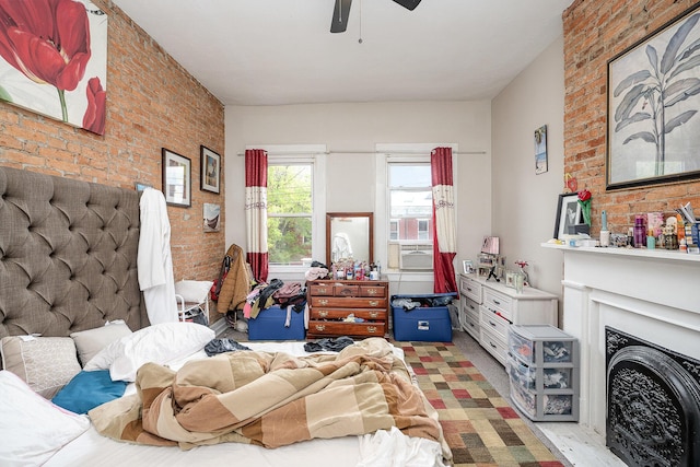 bedroom featuring cooling unit, brick wall, ceiling fan, and a fireplace