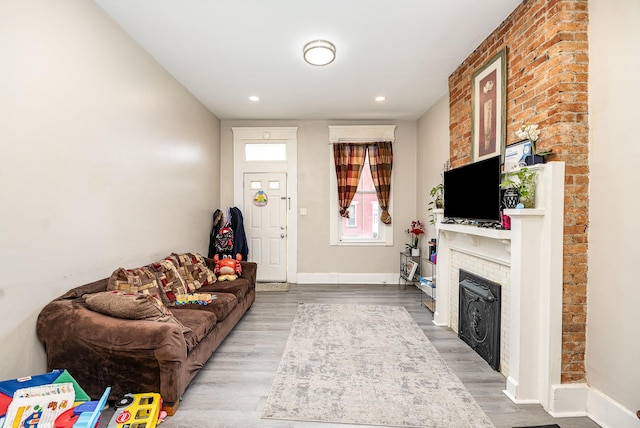 living room with a brick fireplace, recessed lighting, baseboards, and wood finished floors