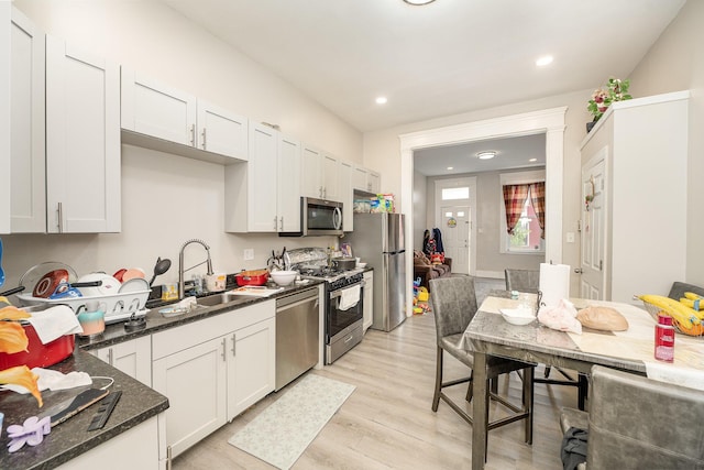 kitchen featuring light wood-style floors, a sink, white cabinetry, and stainless steel appliances