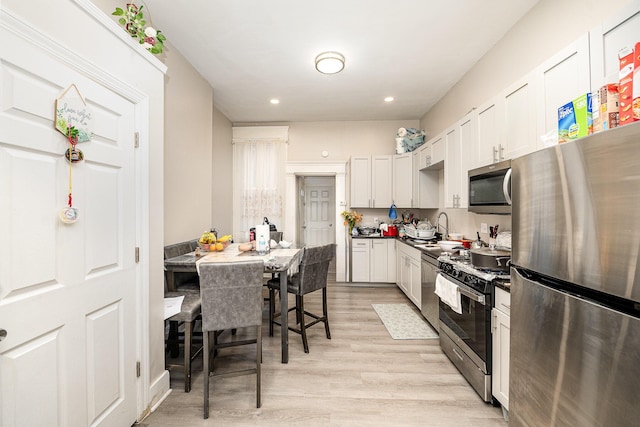 kitchen featuring dark countertops, light wood-type flooring, recessed lighting, a sink, and stainless steel appliances