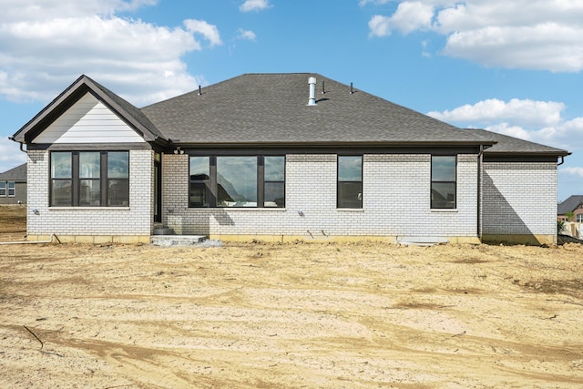 back of property with brick siding and roof with shingles