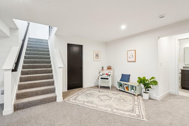living area featuring carpet flooring, stairs, and baseboards