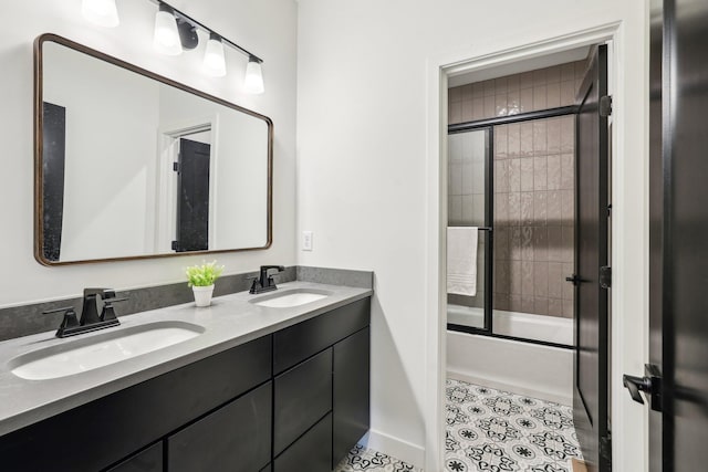 bathroom with enclosed tub / shower combo, double vanity, and baseboards