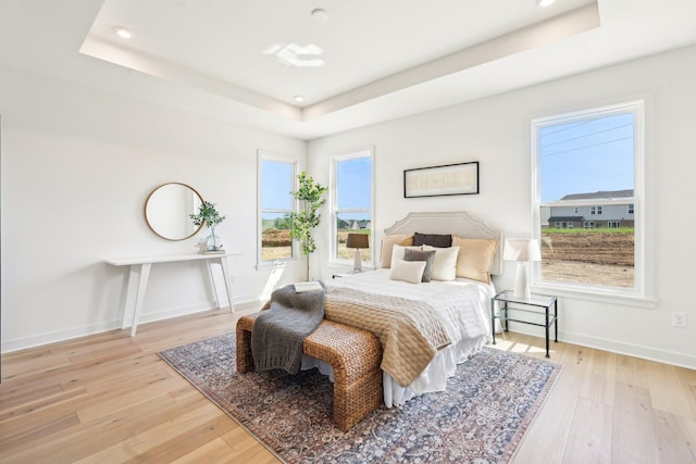 bedroom featuring a tray ceiling, wood-type flooring, baseboards, and recessed lighting