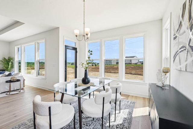 dining area with a chandelier, baseboards, and light wood finished floors