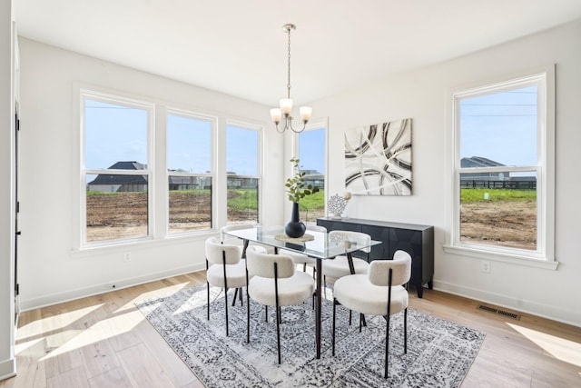 dining area featuring a chandelier, baseboards, and light wood-type flooring