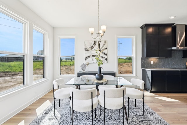 dining room with light wood-style floors, a chandelier, and baseboards
