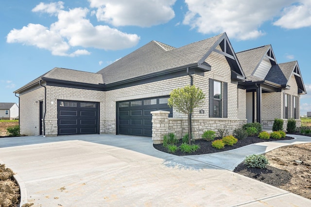 view of side of home featuring an attached garage, concrete driveway, a shingled roof, stone siding, and brick siding
