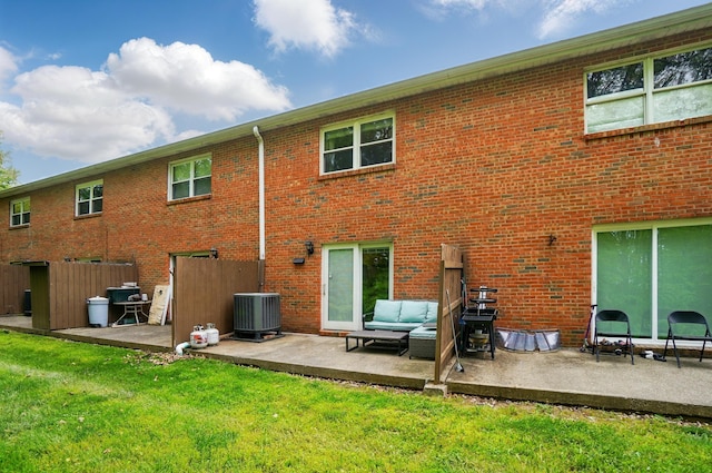 rear view of property with central AC, a patio, a lawn, and brick siding