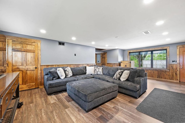 living room featuring wainscoting, wooden walls, wood finished floors, and recessed lighting