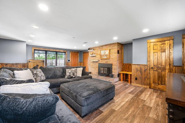 living area with a wainscoted wall, wooden walls, wood finished floors, recessed lighting, and a fireplace
