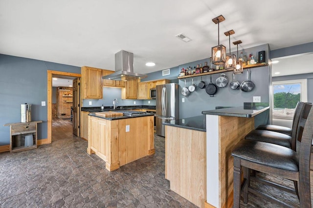 kitchen with stainless steel appliances, dark countertops, island range hood, dark stone finish floors, and light brown cabinets