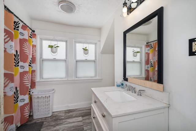 full bath with vanity, a textured ceiling, plenty of natural light, and wood finished floors
