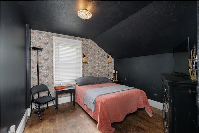 bedroom featuring wood finished floors, vaulted ceiling, baseboards, and a textured ceiling