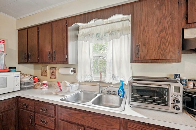 kitchen featuring light countertops, a toaster, white microwave, and a sink