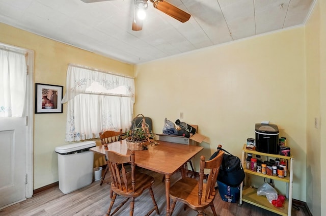 dining space featuring crown molding, wood finished floors, baseboards, and ceiling fan