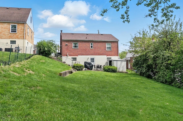 back of property featuring fence, a patio, brick siding, and a lawn