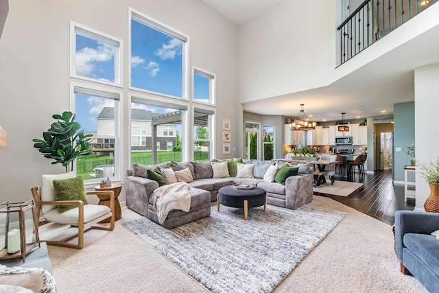 living room featuring a chandelier, a high ceiling, dark wood-style flooring, and baseboards