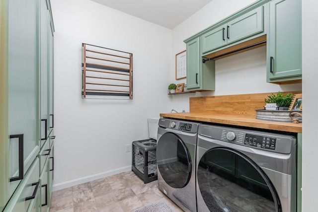 laundry room featuring washing machine and clothes dryer, cabinet space, and baseboards