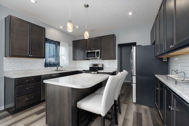 12062 Ambruzzi Dr, Walton, KY 41094 - kitchen featuring appliances with stainless steel finishes, a sink, backsplash, a kitchen bar, and a center island