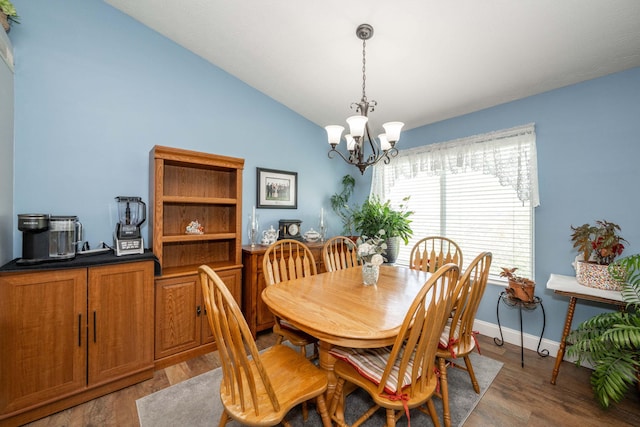 dining space featuring vaulted ceiling, a notable chandelier, light wood-type flooring, and baseboards
