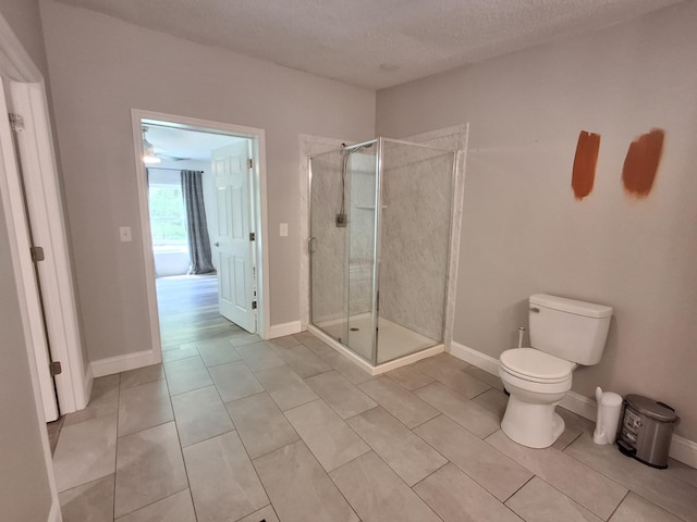 full bath with a textured ceiling, toilet, baseboards, a shower stall, and tile patterned floors