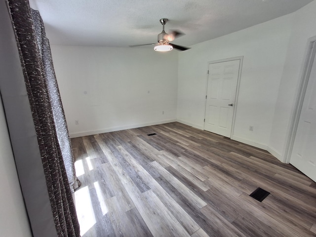 spare room featuring visible vents, wood finished floors, baseboards, and ceiling fan