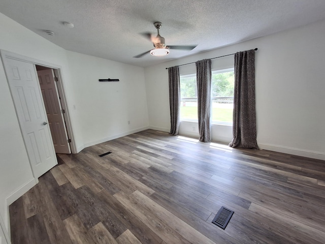 empty room featuring wood finished floors, a ceiling fan, a textured ceiling, visible vents, and baseboards